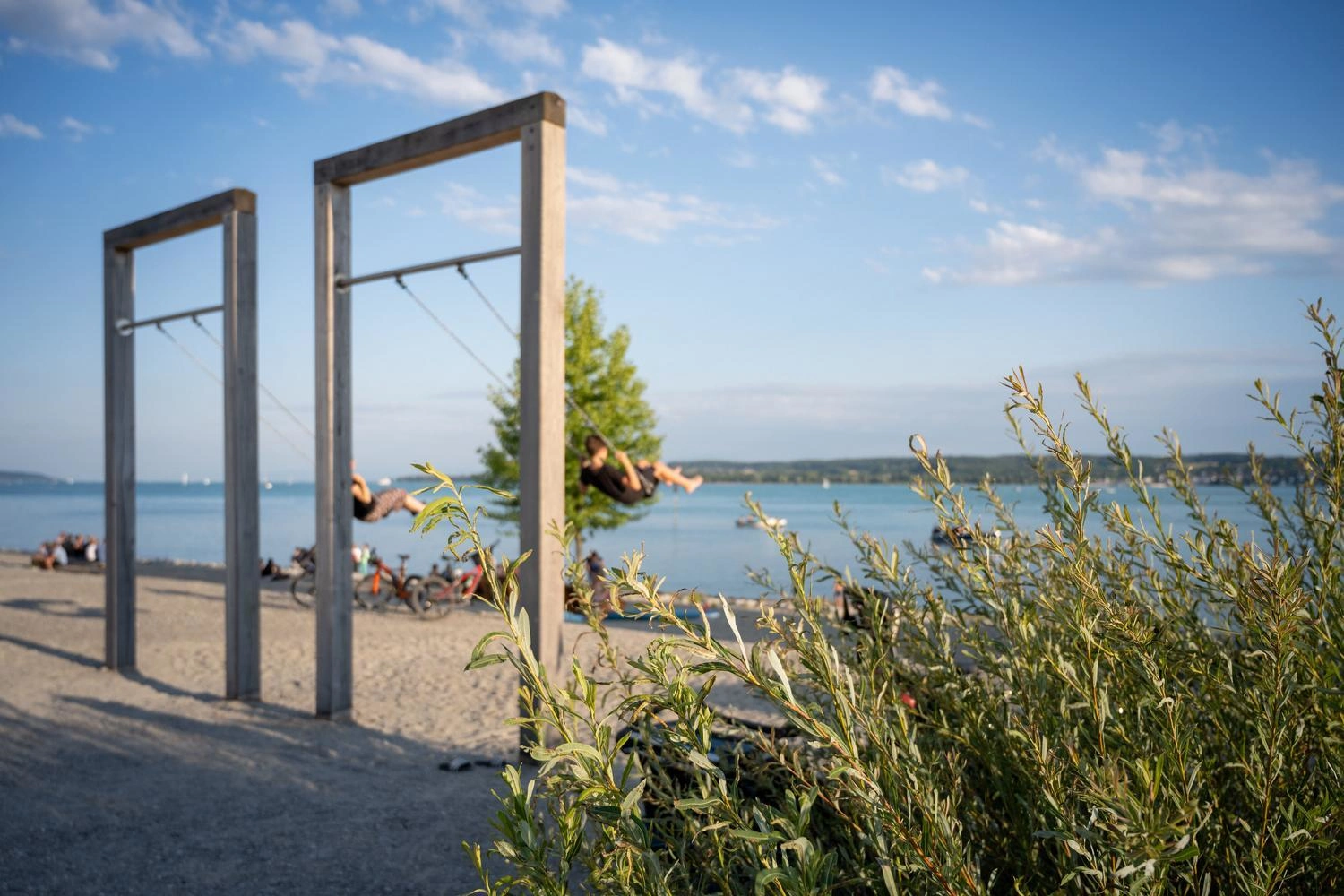 Large wooden swings on the shore of Lake Constance in Überlingen, overlooking the water.