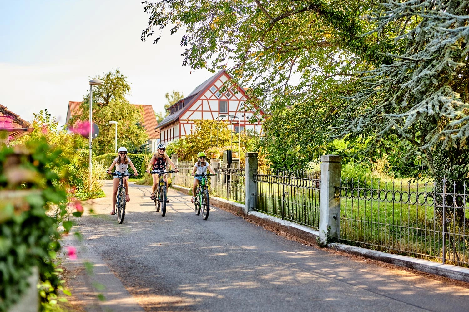 Drei fahrradfahrende Personen radeln durch den idyllischen Ort Seefelden.