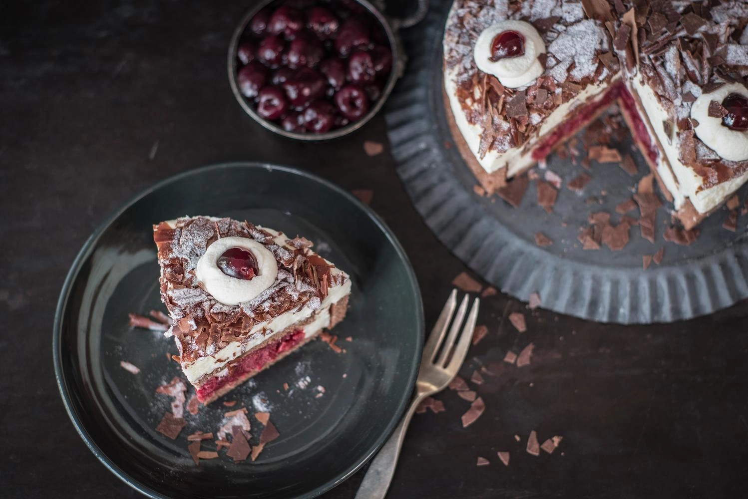 A slice of Black Forest gateau next to the rest of the cut cake.