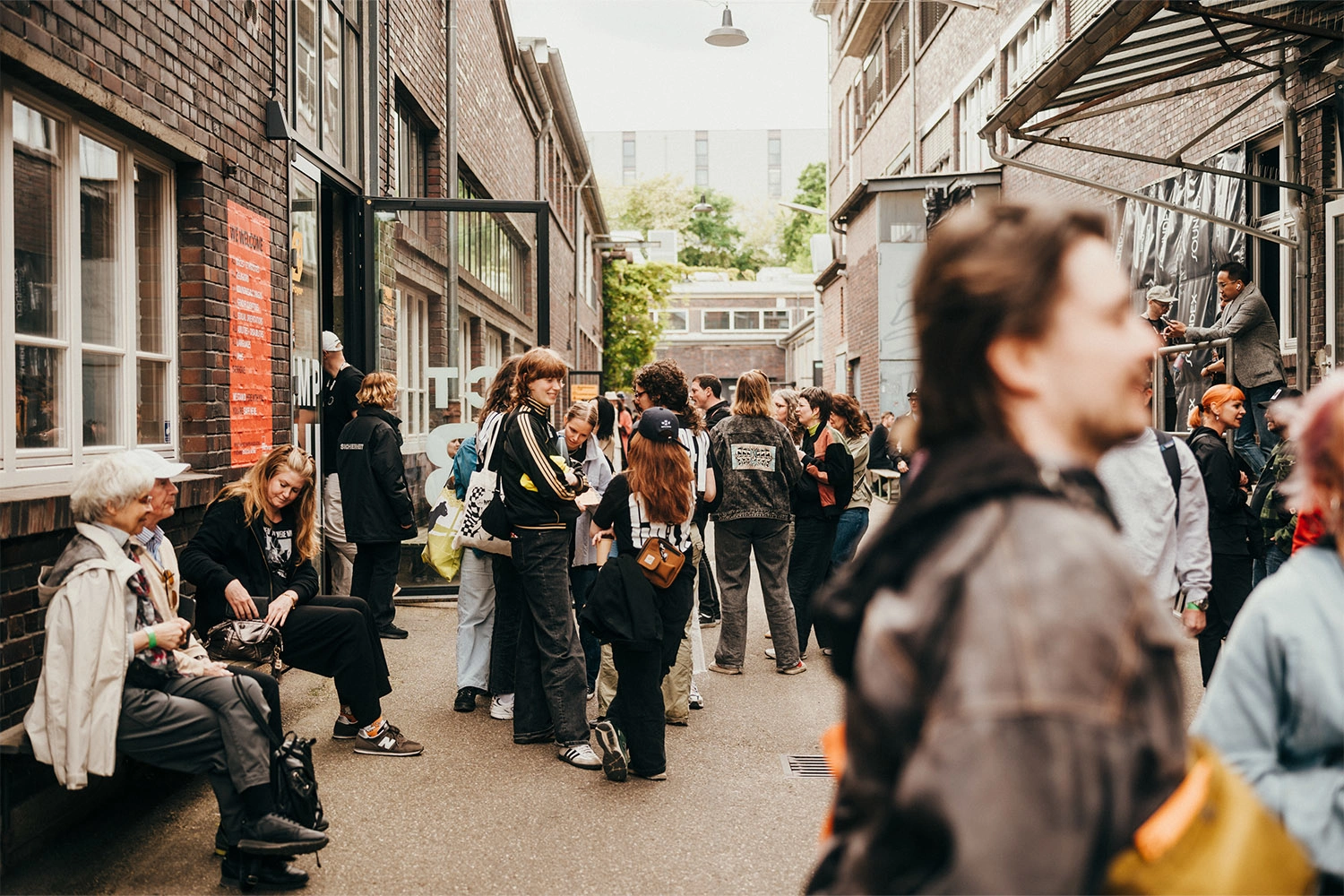 Besucher stehen und sitzen vor dem Wizemann Areal in Stuttgart beim Festival About Pop; zeigt Ankunft, Austausch und Wartesituation am Eingang.