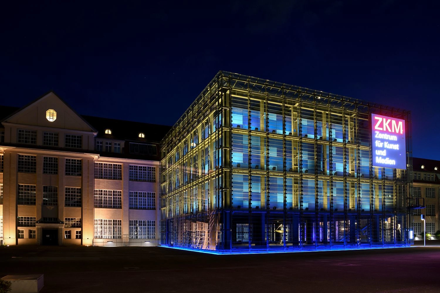 Das ZKM | Zentrum für Kunst und Medien in Karlsruhe bei Nacht, die Glasfassade des Kubus leuchtet blau