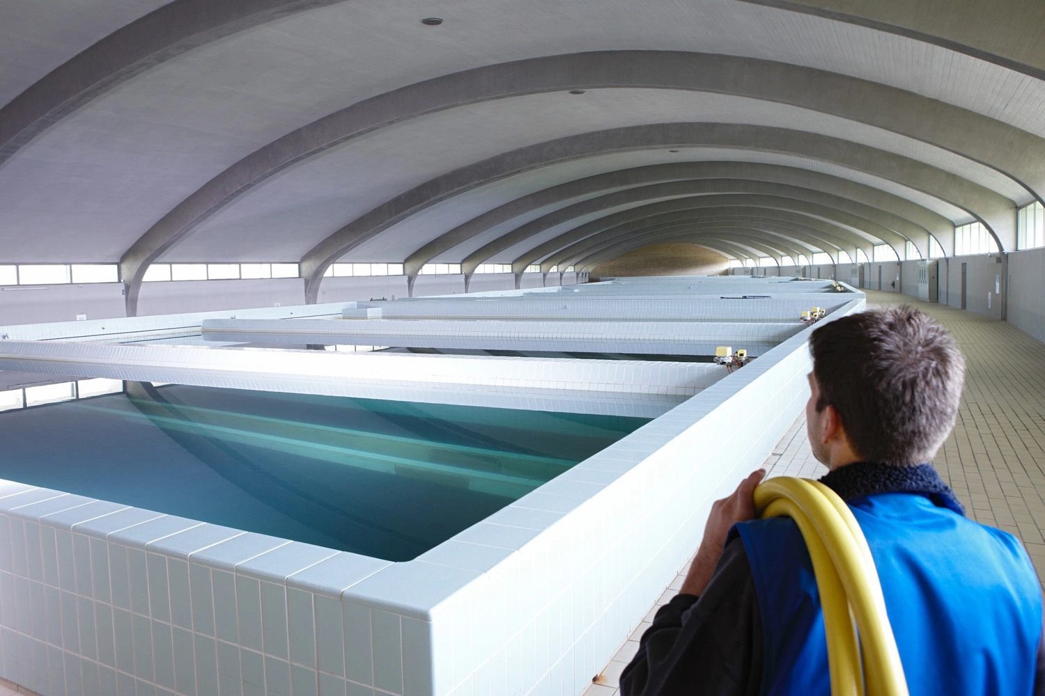 Ein Mann steht in einer riesigen Halle, in der in vielen Becken Wasser gefiltert wird.