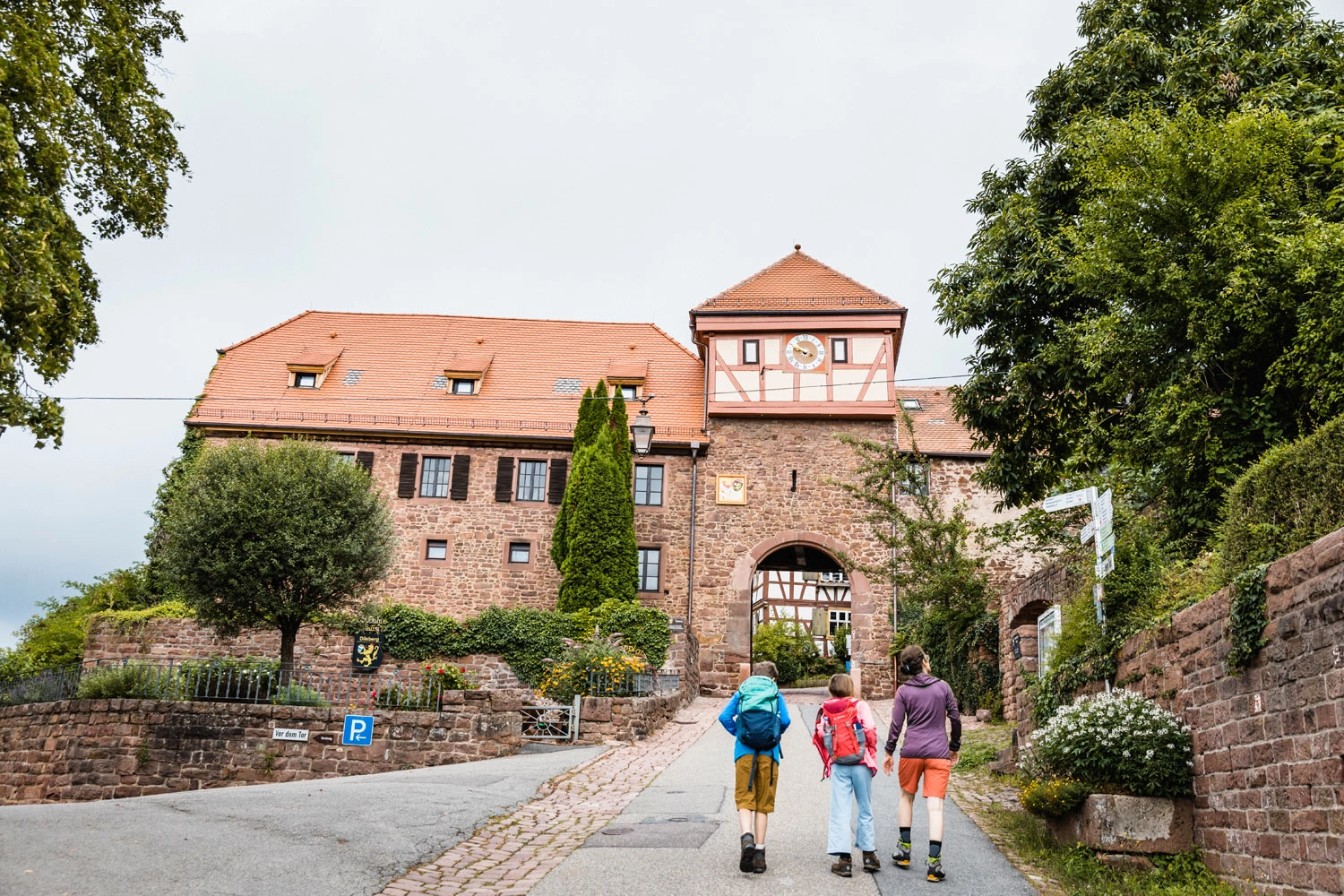 Eine Mutter wandert mit ihren Kindern Richtung dem Eingangstor einer Burg.