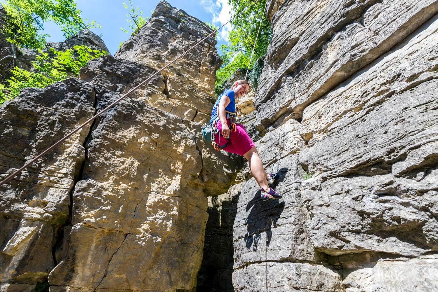 Eine Kletterin seilt sich an einem großen Felsen ab.