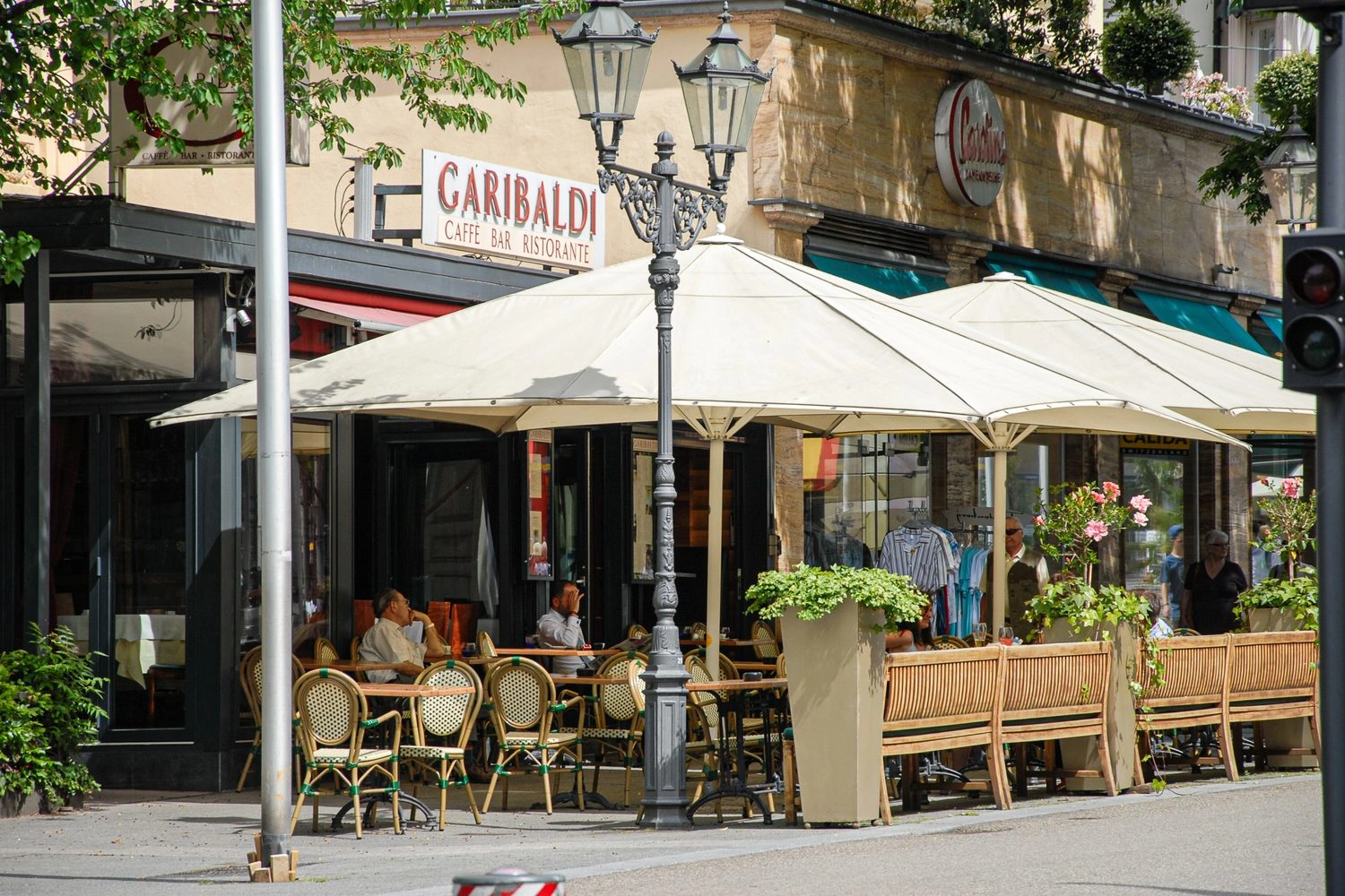 Terrasse eines Restaurants, die großen Sonnenschirmen überspannt ist.
