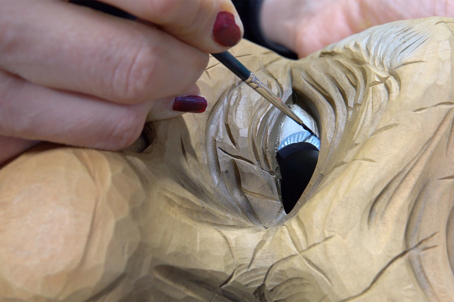 The eye of the mask gets painted with a fine brush.