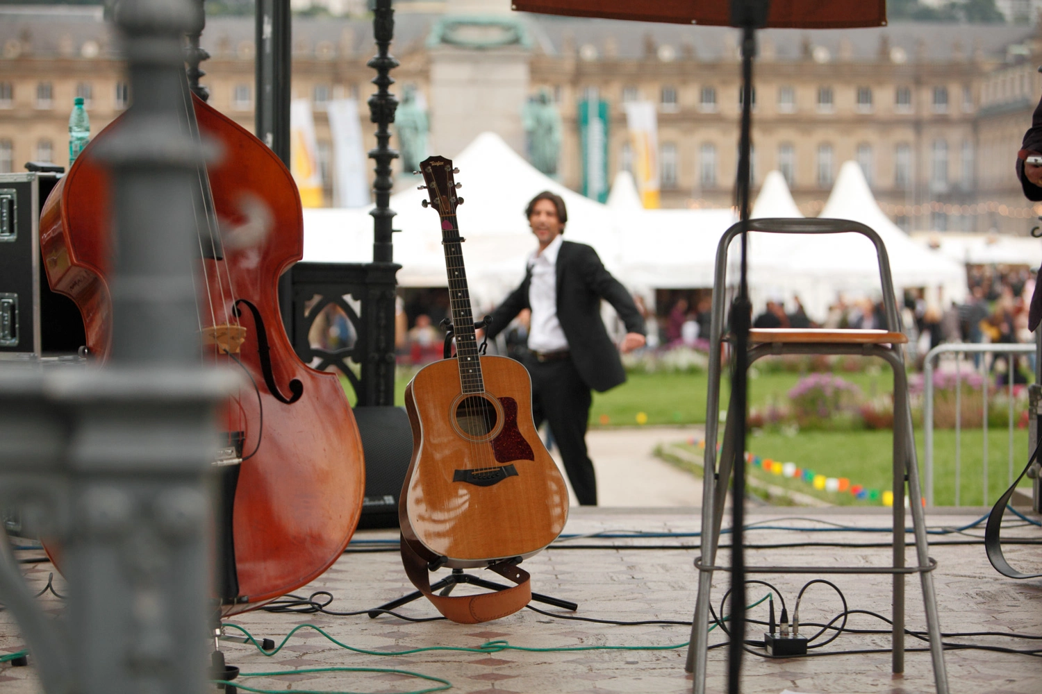 Musiker steht hinter einer Gitarre und einem Cello. Die Instrumente stehen unter einem Pavillon auf dem Stuttgarter Schlossplatz.