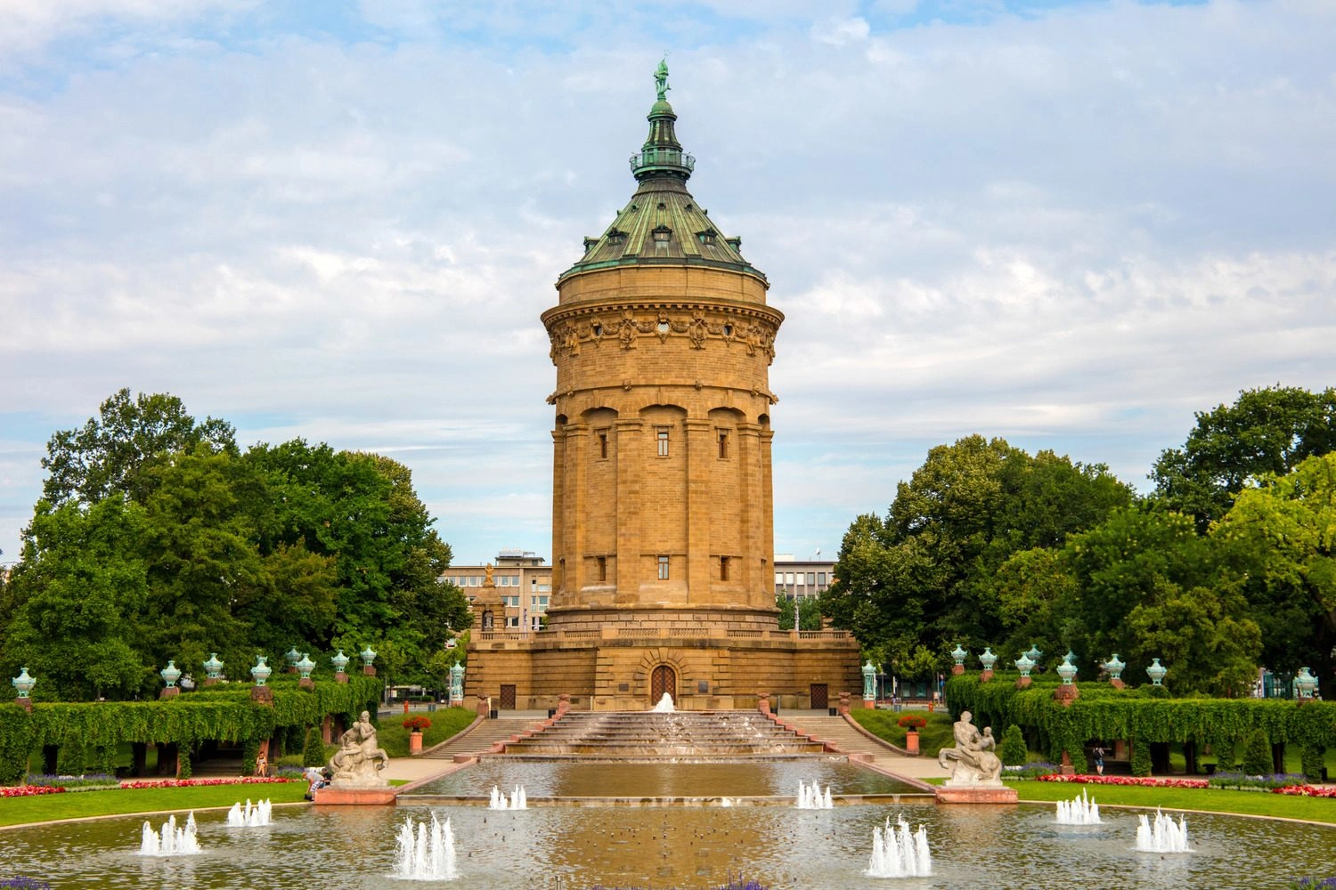 Turm in einer Parkanlage, vor dem sich ein großes Wasserspiel befindet