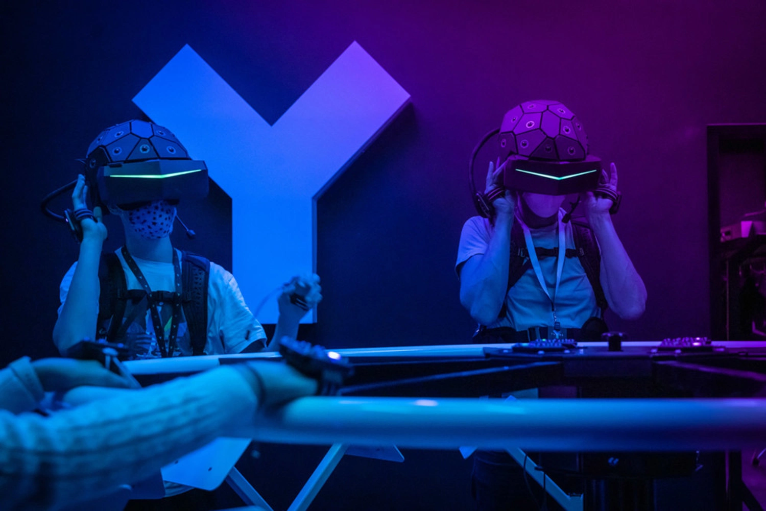 Two children with VR goggles and other VR equipment in a darkened room.