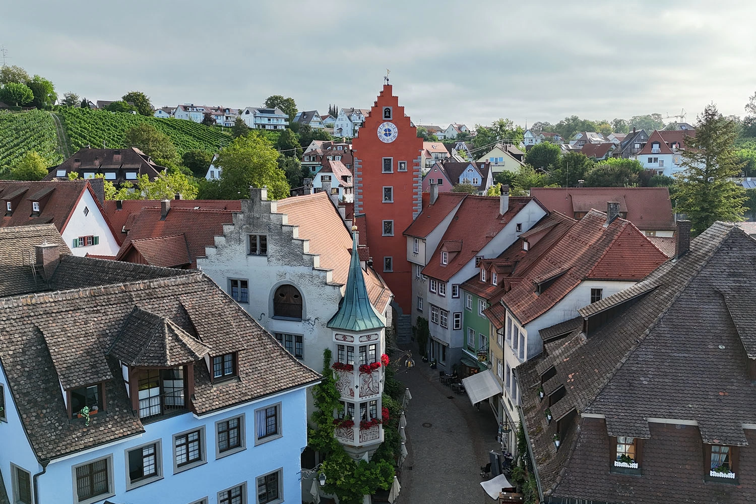 Altstadt von Meersburg mit roten Ziegeldächern und dem roten Stadttor mit Uhrturm; vermittelt historisches Flair und Sehenswürdigkeiten der Region.
