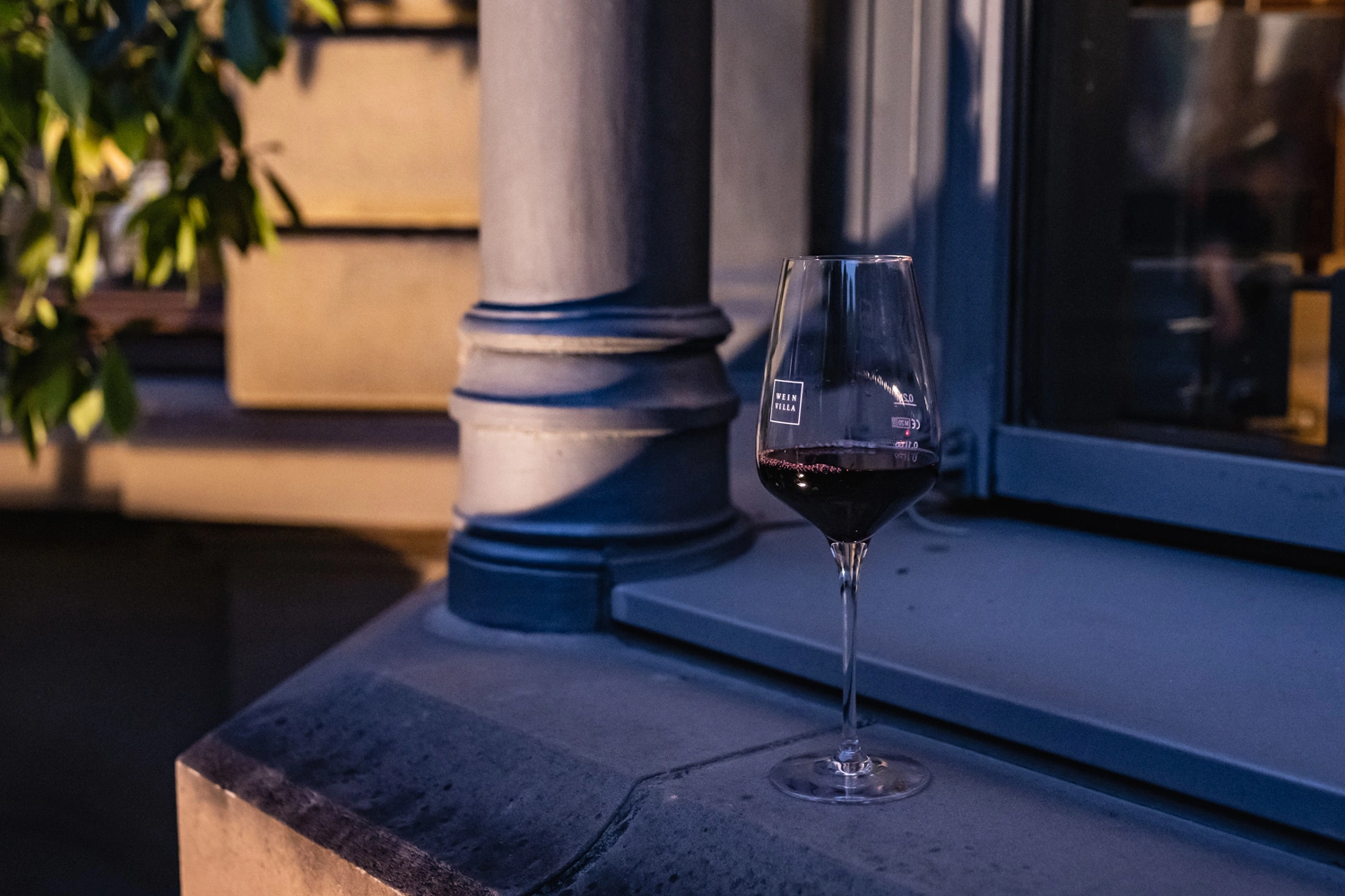 A wine glass with Ritwein stands on a stone windowsill.