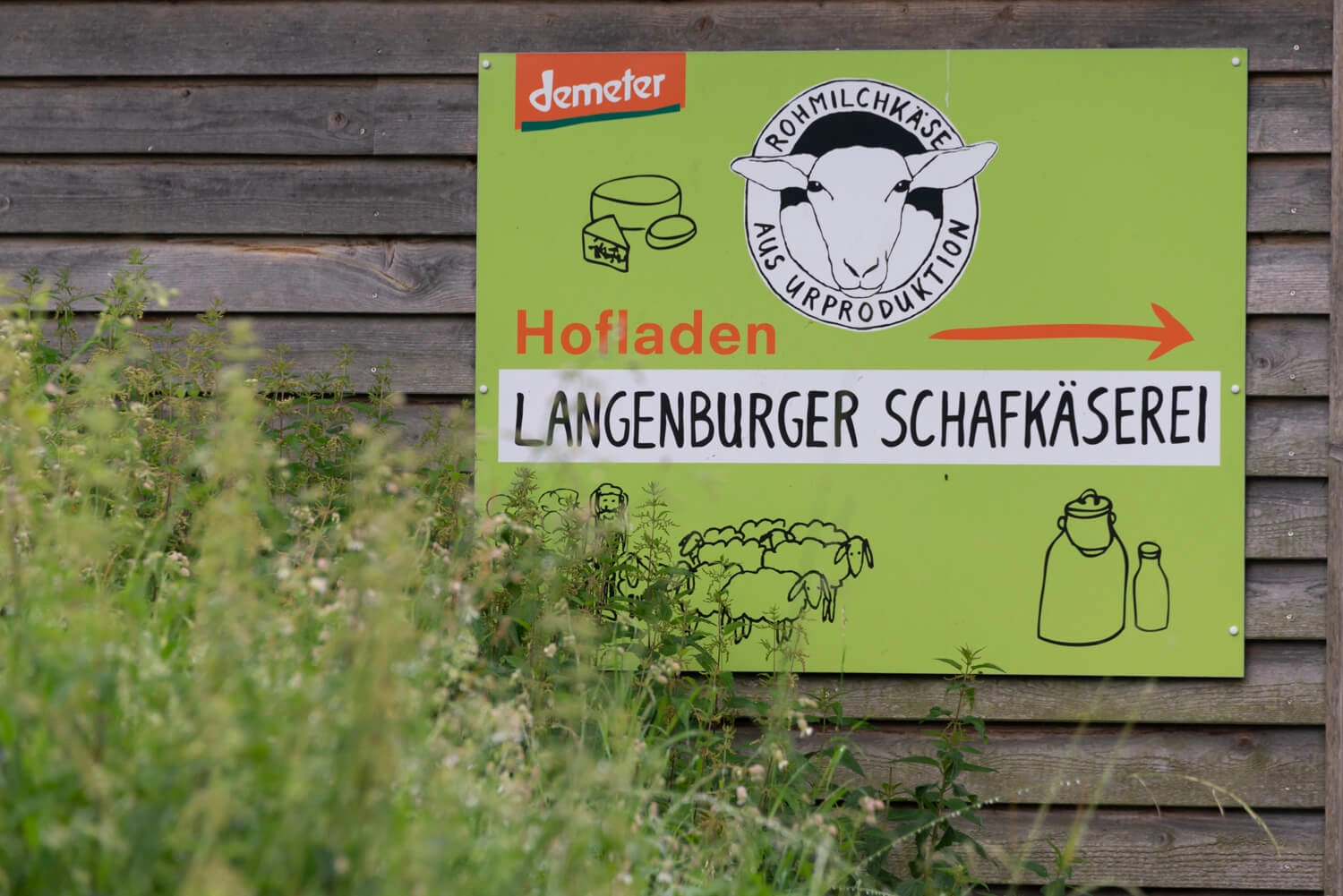 Sign on a house wall pointing the way to a farm store