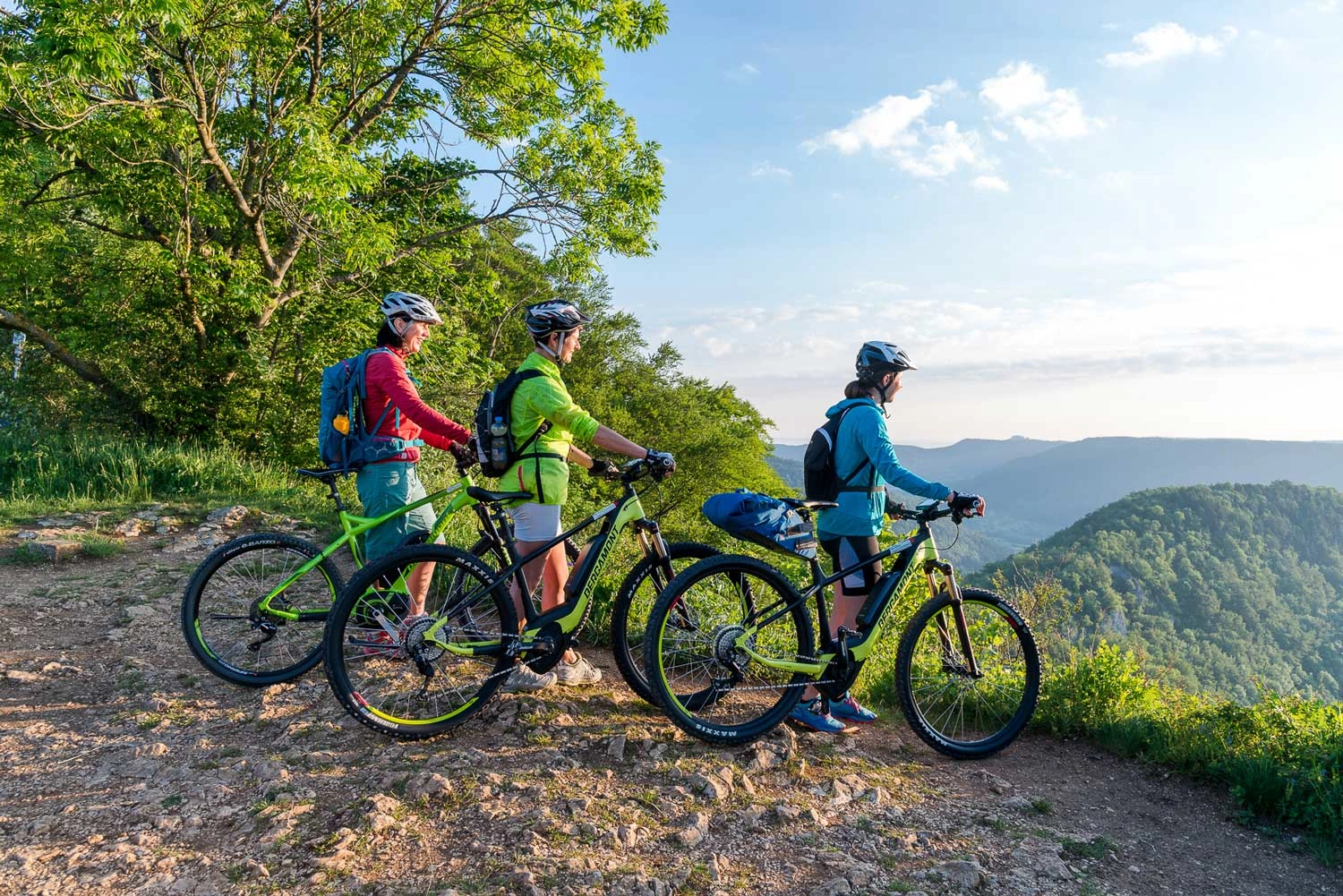 Drei Mountainbiker stehen an der Kante eines Bergs und genießen die Aussicht.