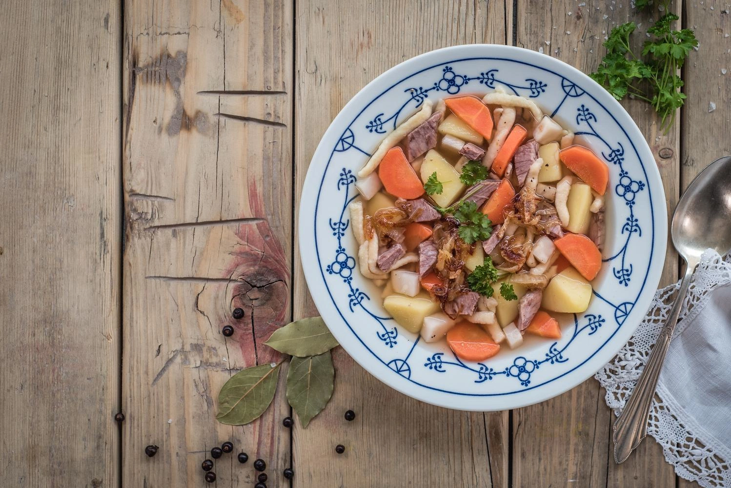 Top view of a plate full of hearty stew on a rustic wooden table.