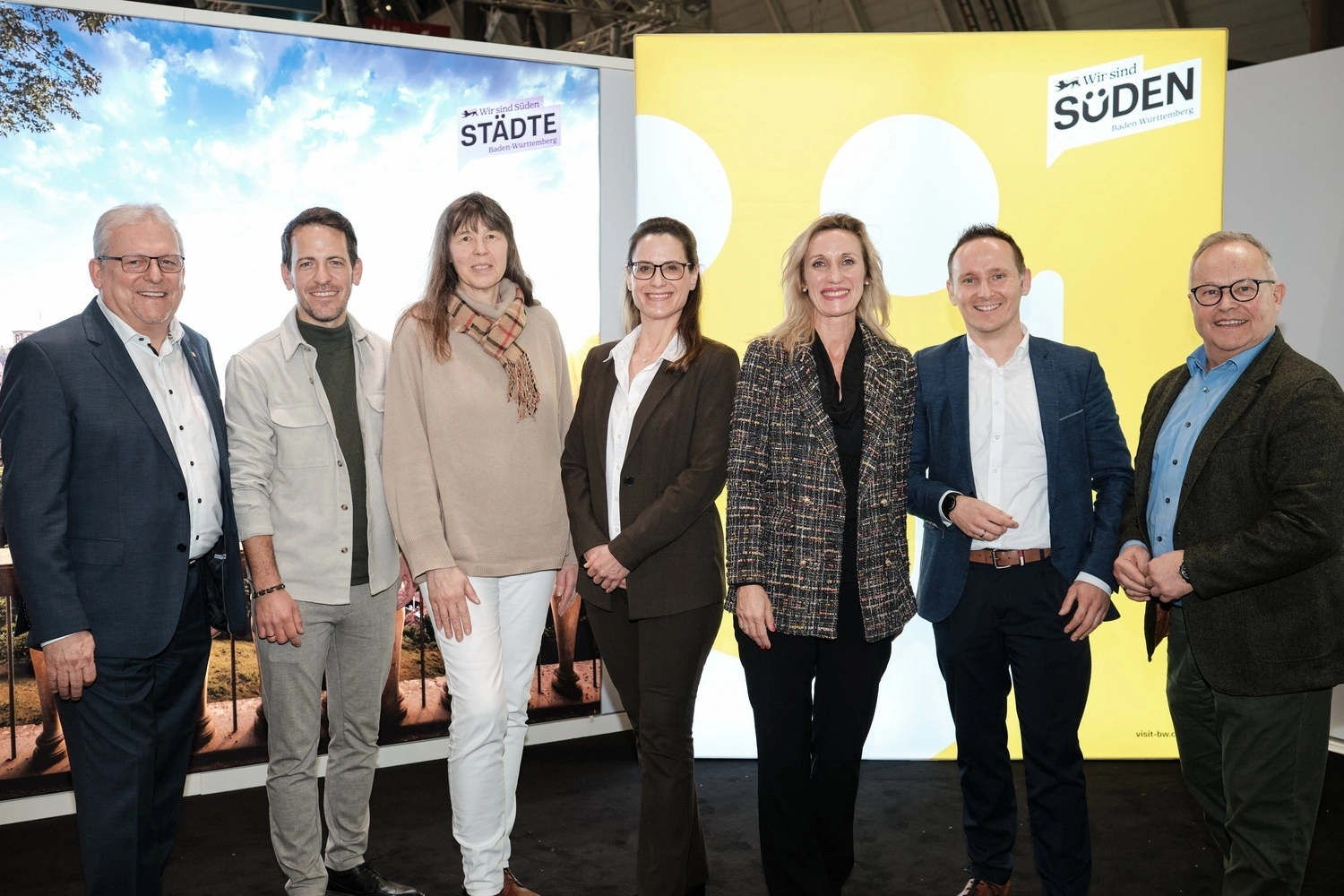 Eine Gruppe von Geschäftspartnern posiert für ein Foto vor Stellwänden.