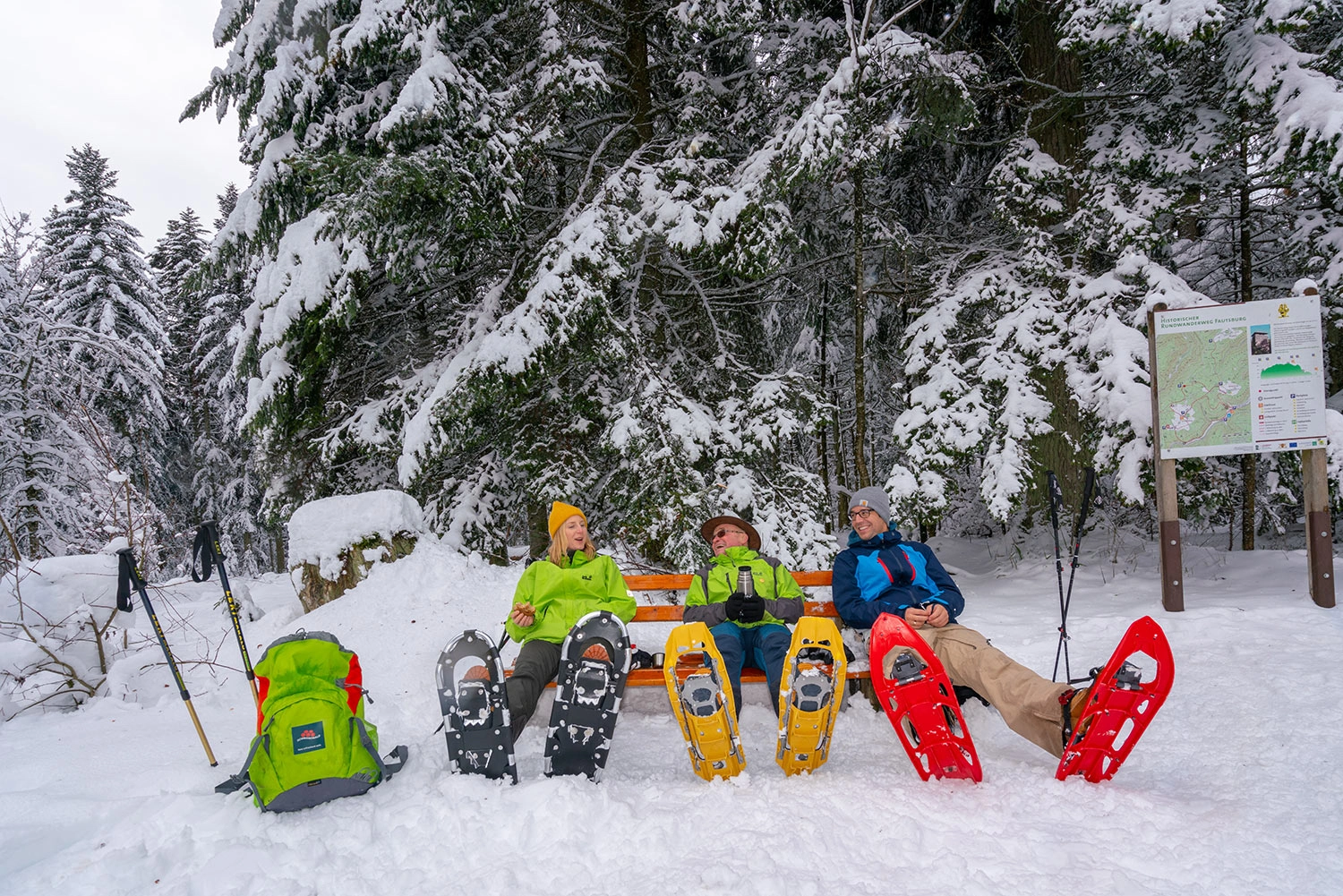 Three people sit on a bench in the snow and take a short tea break.