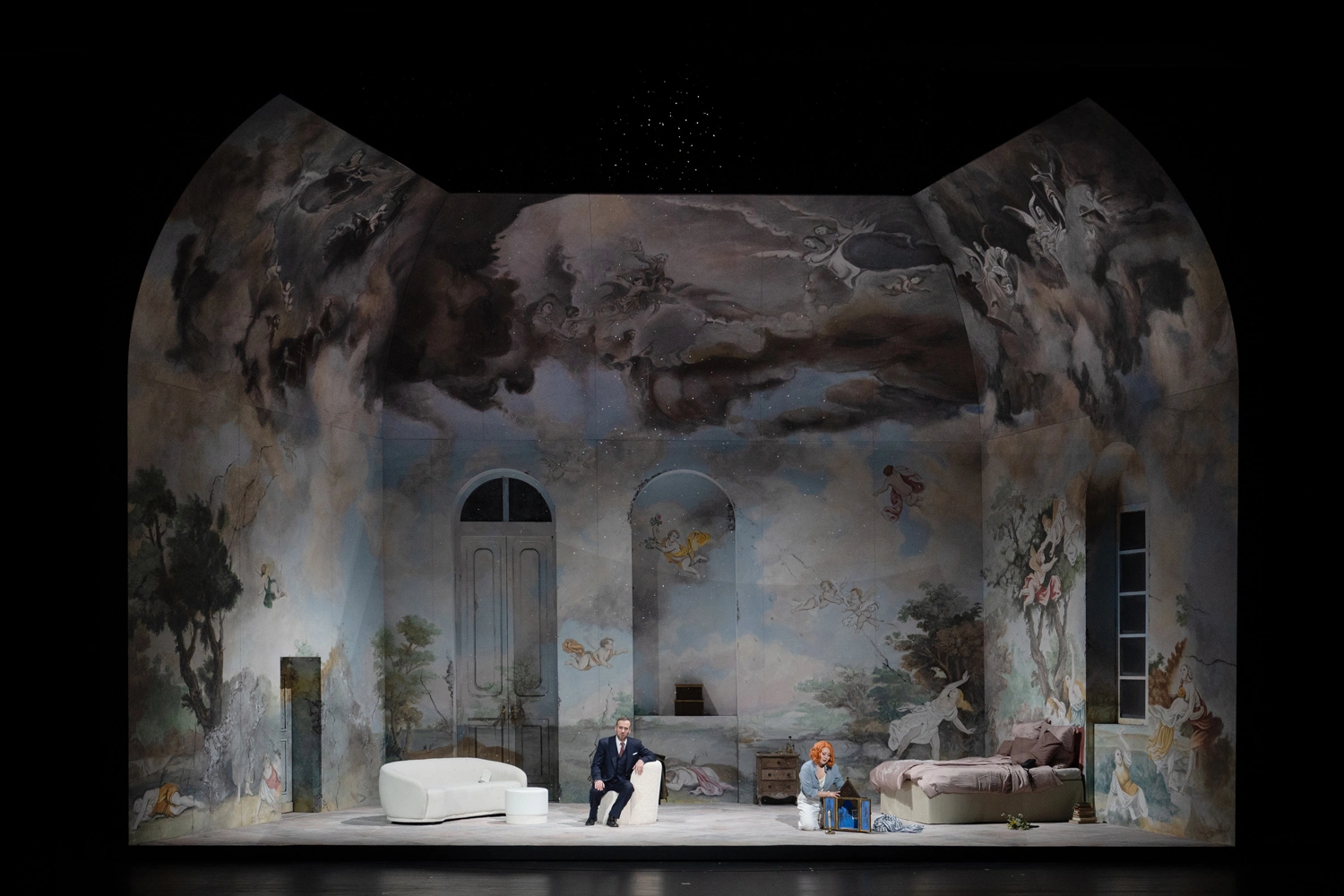 Stage set for a theater performance with elaborately painted walls depicting clouds, angels, and landscapes.