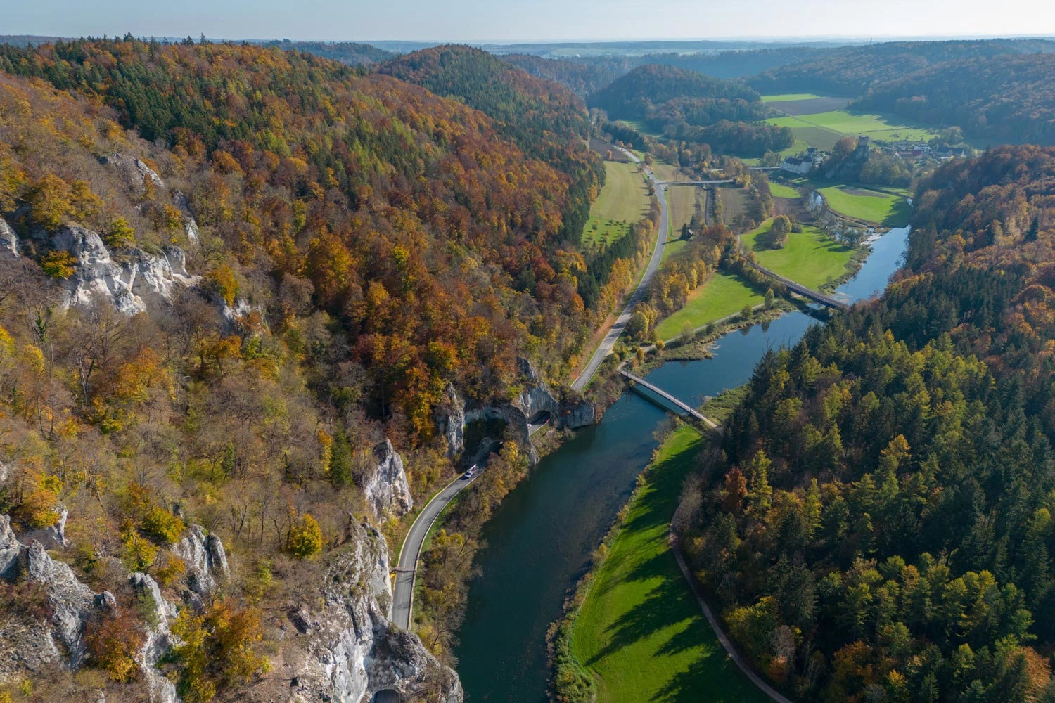  View of the Danube from far above, surrounded by autumnal forest.