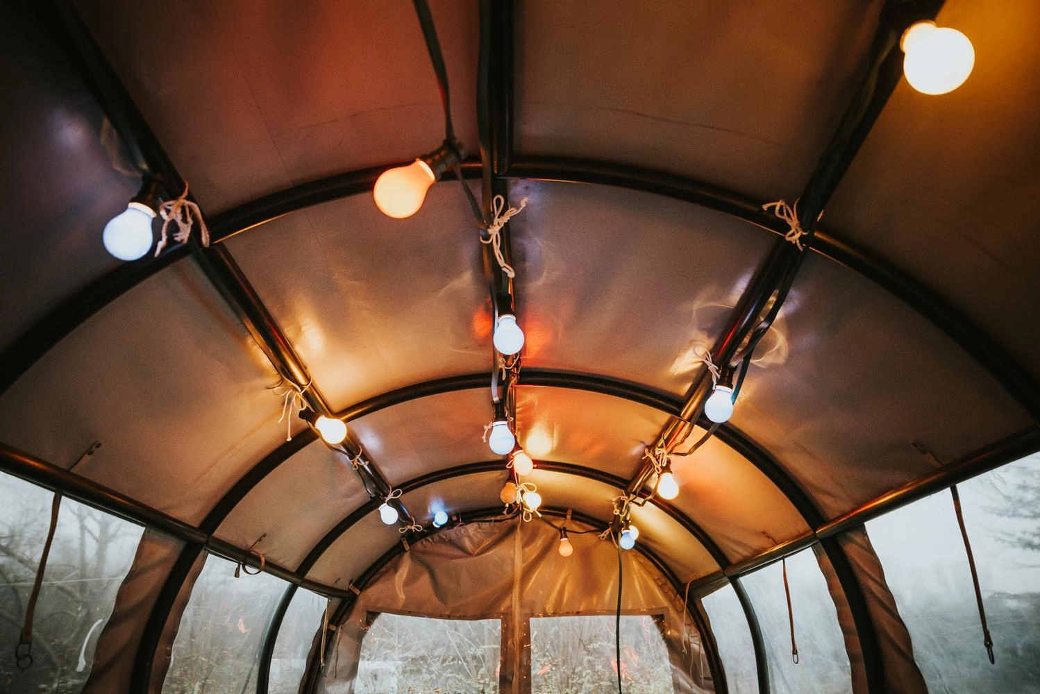 Innenansicht eines überdachten Planwagens mit Lichterketten, die den Raum warm und stimmungsvoll beleuchten.