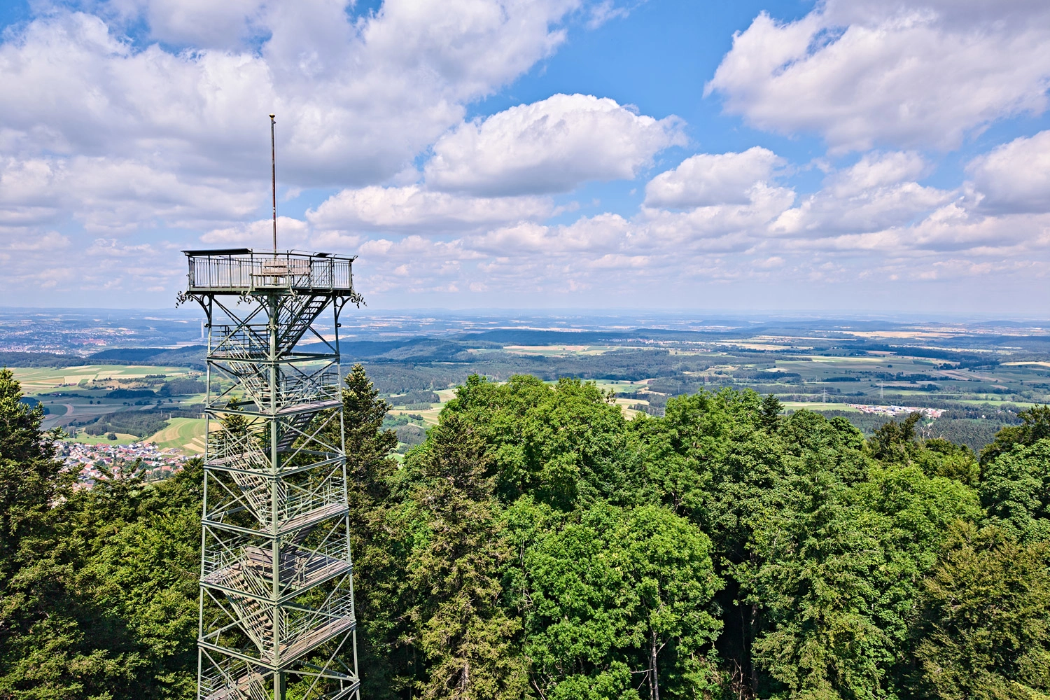 A metal observation tower on a wooded ridge in the Swabian Alb, offering sweeping views over fields and valleys.