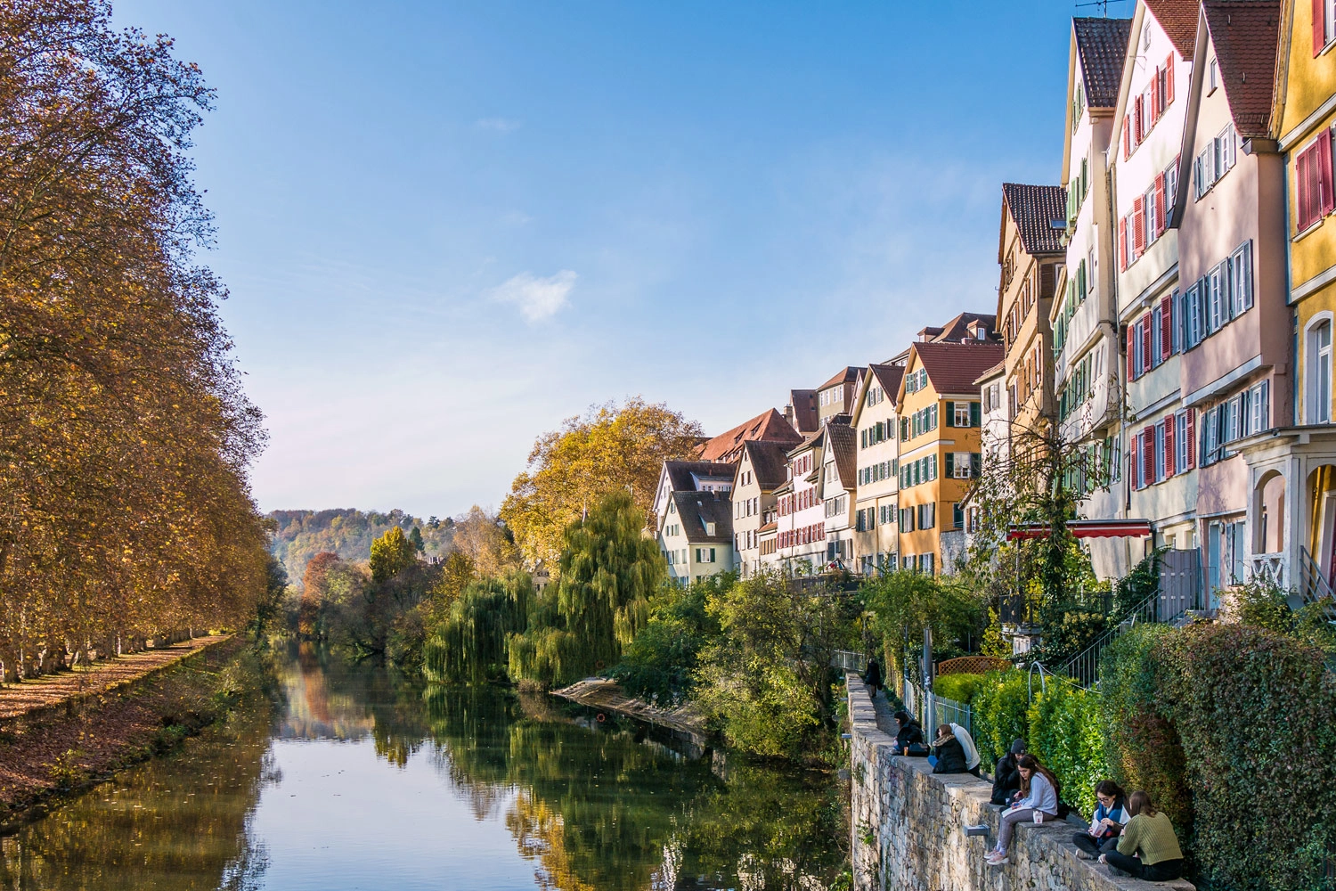 Ein Fluss schlängelt sich idyllisch a einer Ortschaft mit Fachwerkhäusern vorbei.