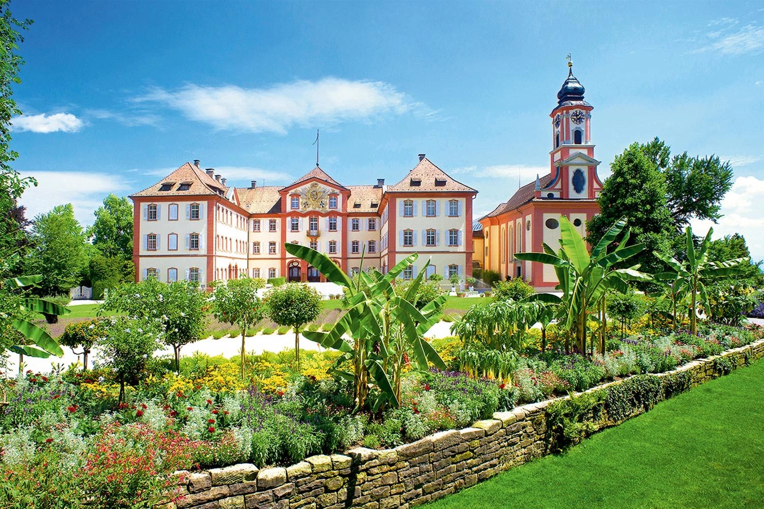 Blick auf eine Schlossanlage in einem tropisch blühenden und grünen Garten
