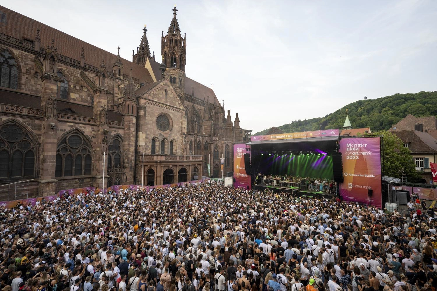Eine feiernde Menschenmenge genießt ein Open-Air-Konzert vor dem Freiburger Münster.