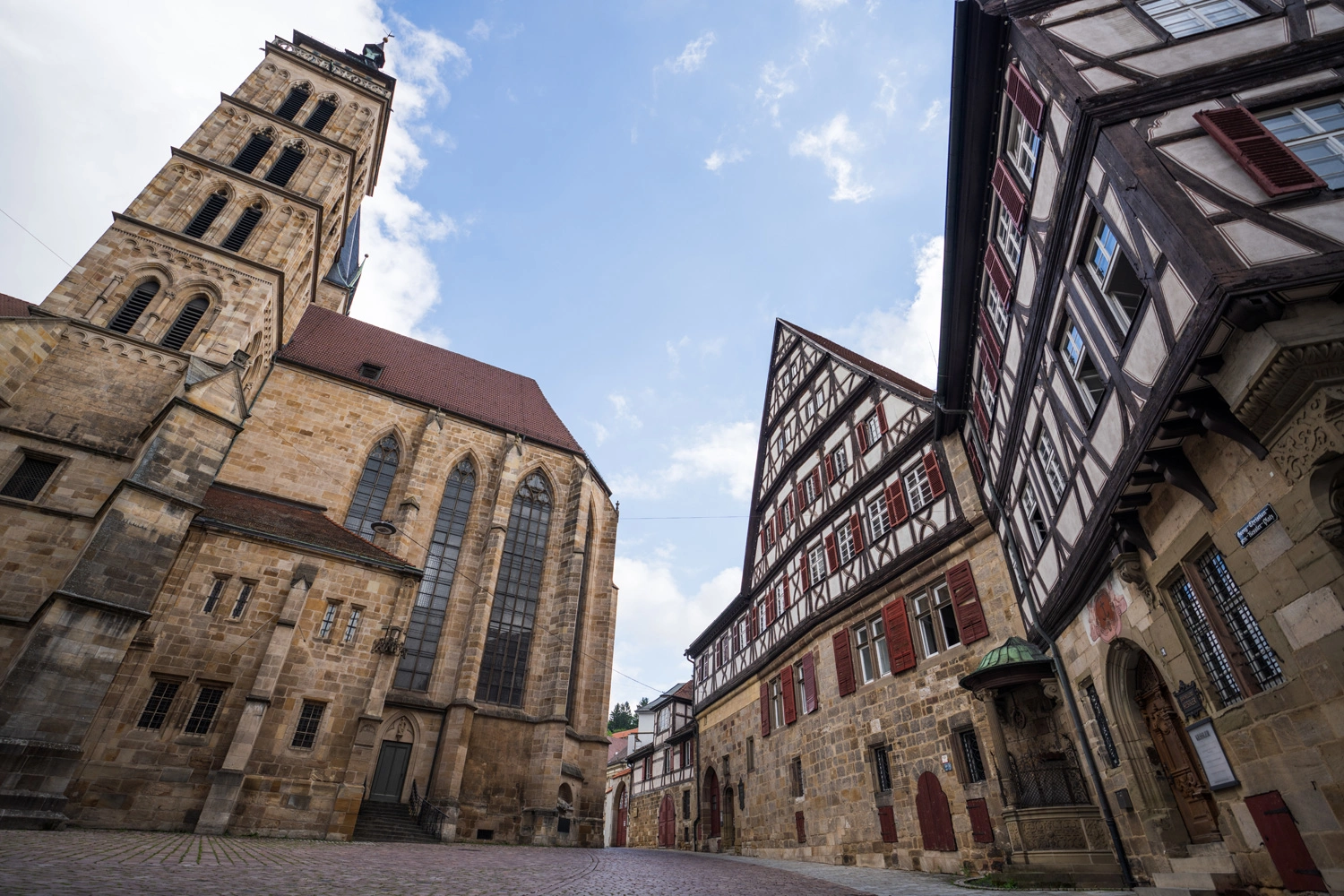 Historic old town with large Gothic church and striking half-timbered houses, seen from a slightly oblique perspective under blue skies.