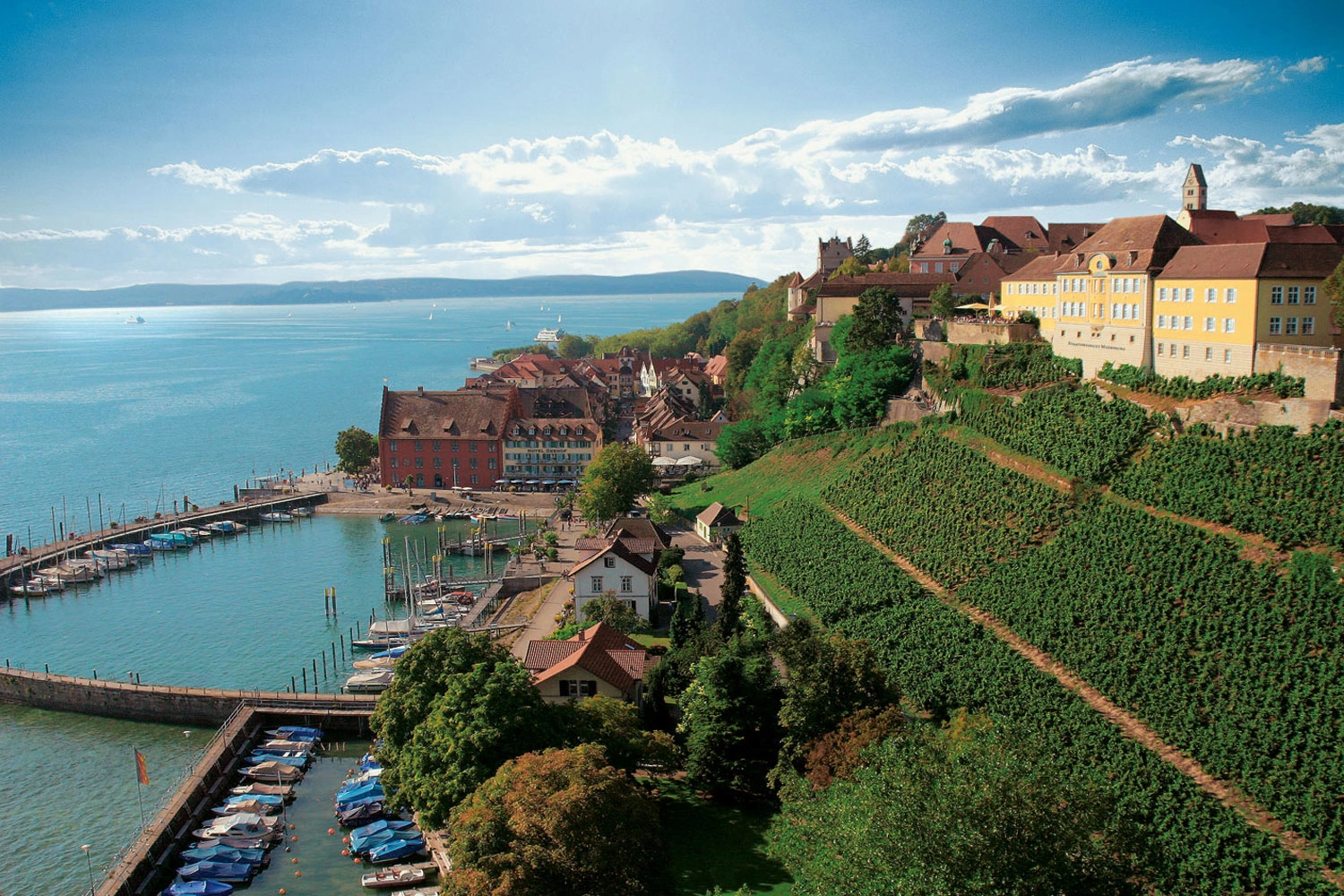 View of the Meersburger Rieschen steep slope on Lake Constance. Meersburg Castle sits enthroned on top of the hill. Lake Constance lies at the foot of the mountain. You can see the harbour.