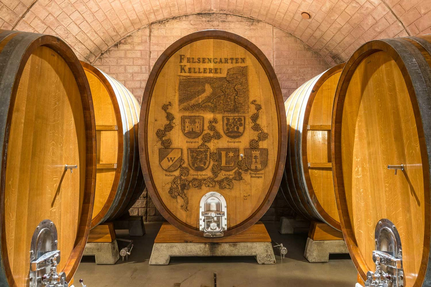 Im Weinkeller einer Weinkellerei stehen viele riesige Holzfässer.