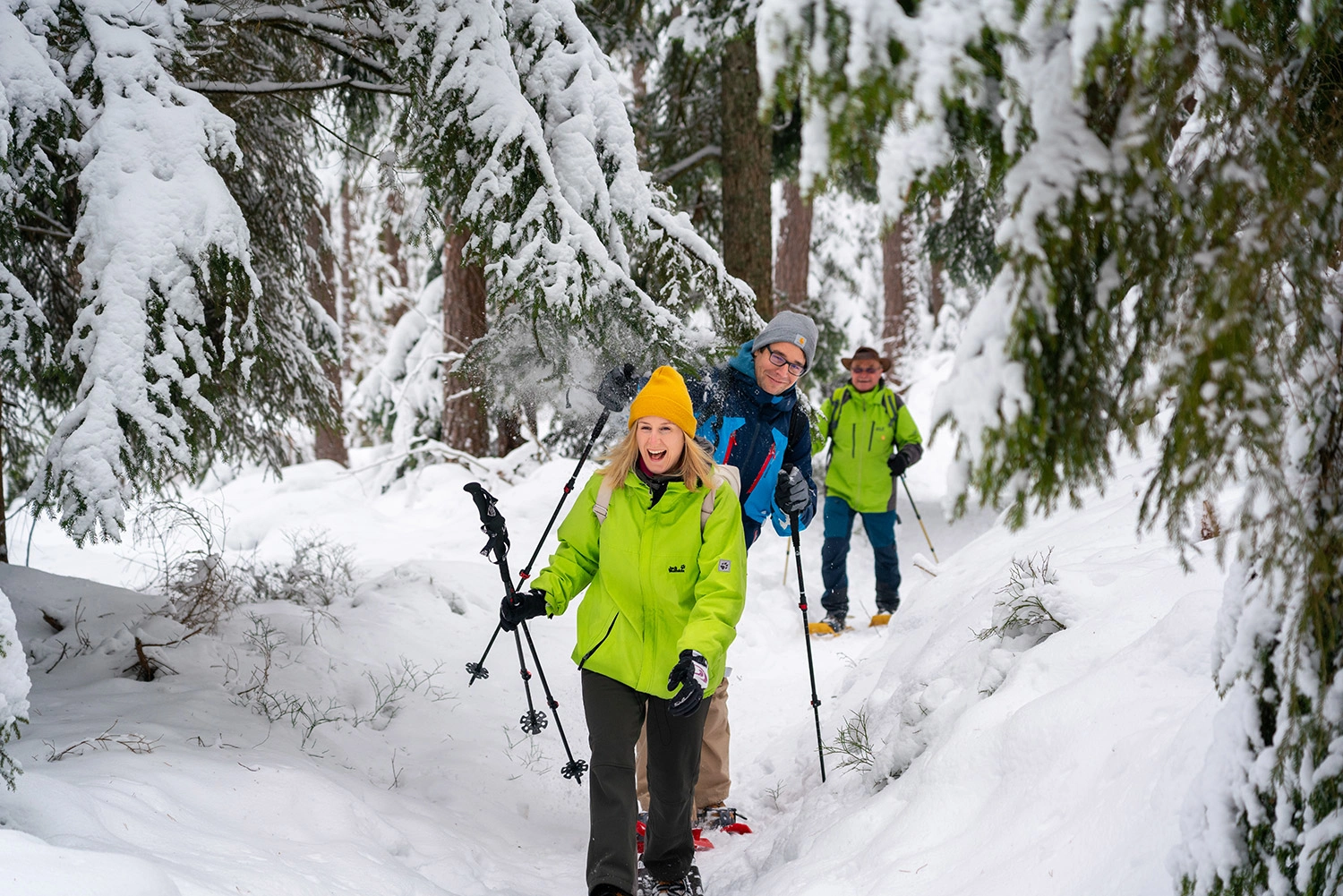 Three people snowshoeing in the snow-covered Black Forest.