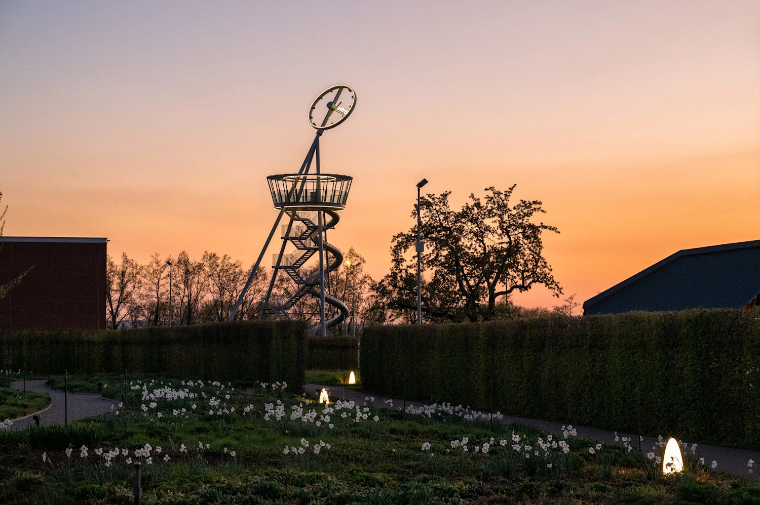 Ein metallener Turm mit Rutsche im orangenen Sonnenuntergang.