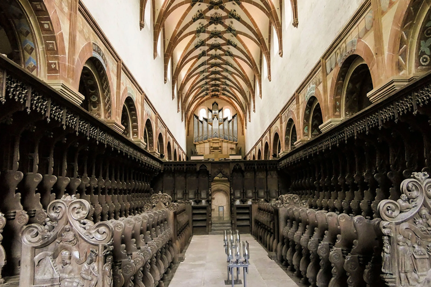 Nave of Maulbronn Monastery church with richly carved choir stalls, a high ribbed vault and an organ.