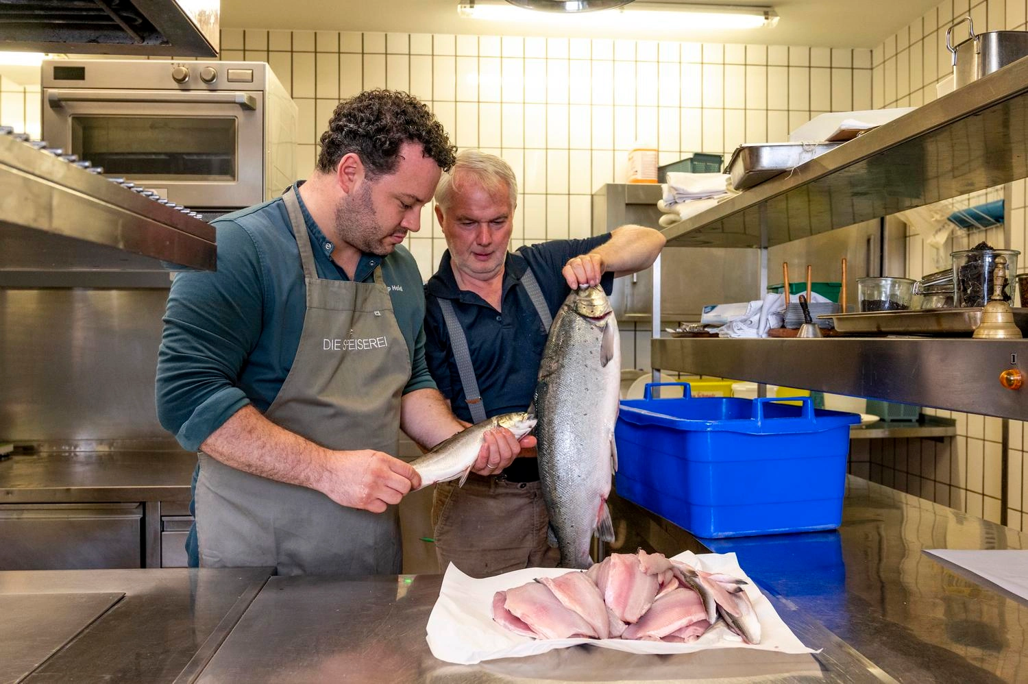 Ein Küchenchef mit Schürze begutachtet eingegangene Ware - in diesem Fall frische Fische.