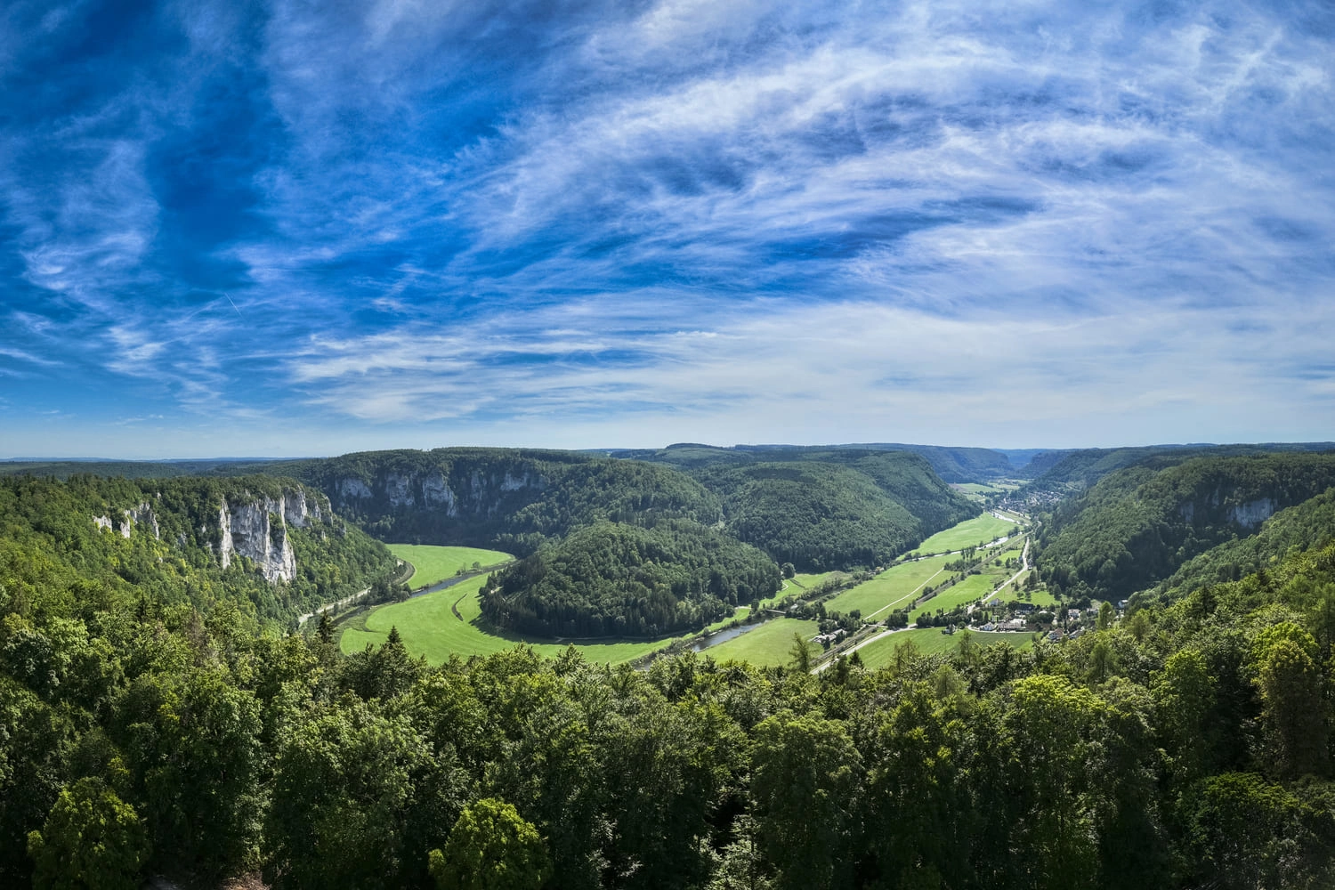 Ausblick über das Donautal mit vielen Bäumen, Wiesen und einem Fluss.
