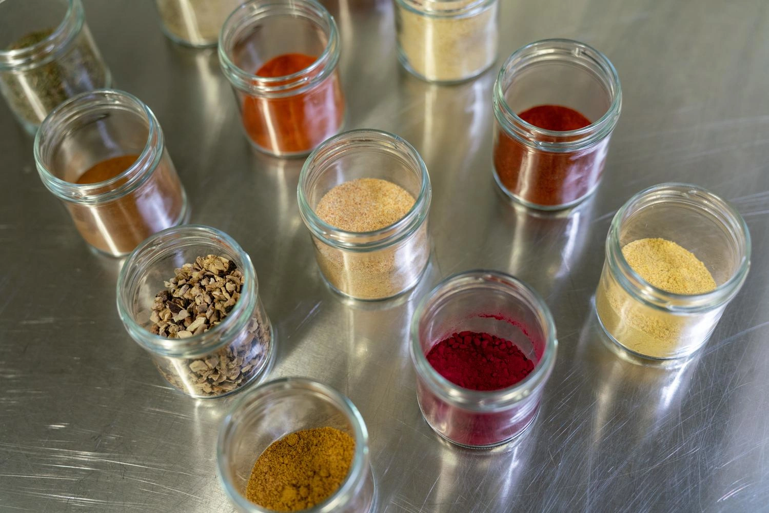  Several small glass containers with different colored spices inside.