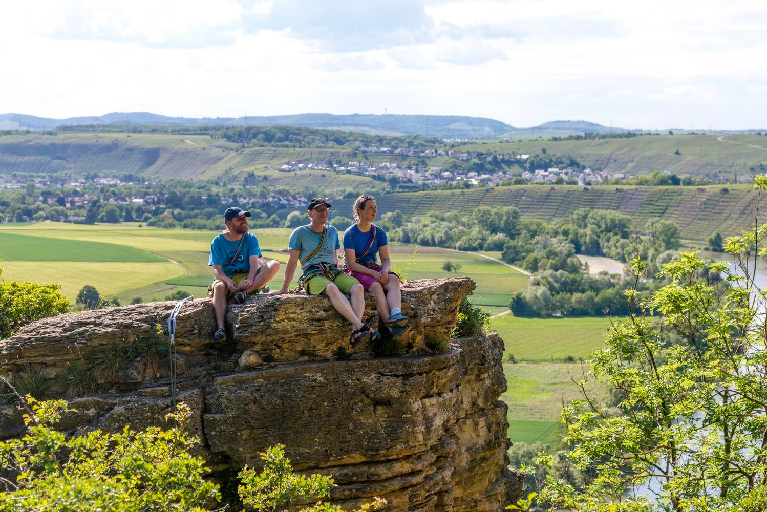 Drei Kletterer machen eine Pause auf einem Felsen und genießen die Aussicht.