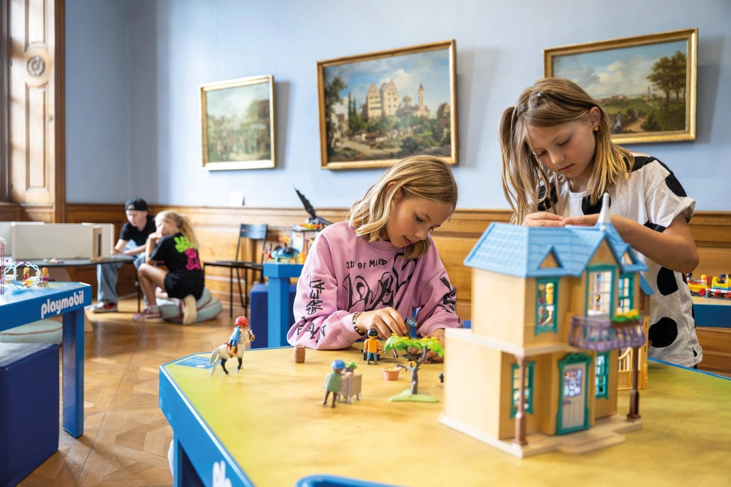 Zwei Mädchen spielen an einem Tisch mit Playmobil.