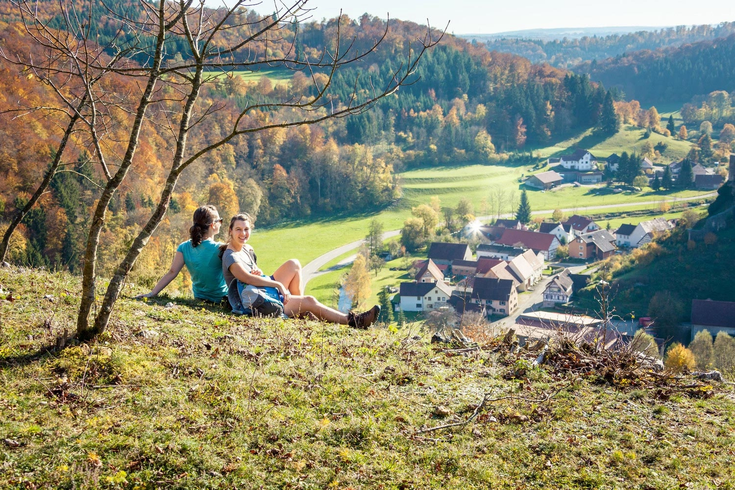 Ausblick über das herbstliche Lautertal auf der Schwäbischen Alb mit Wandernden an einem Aussichtspunkt.