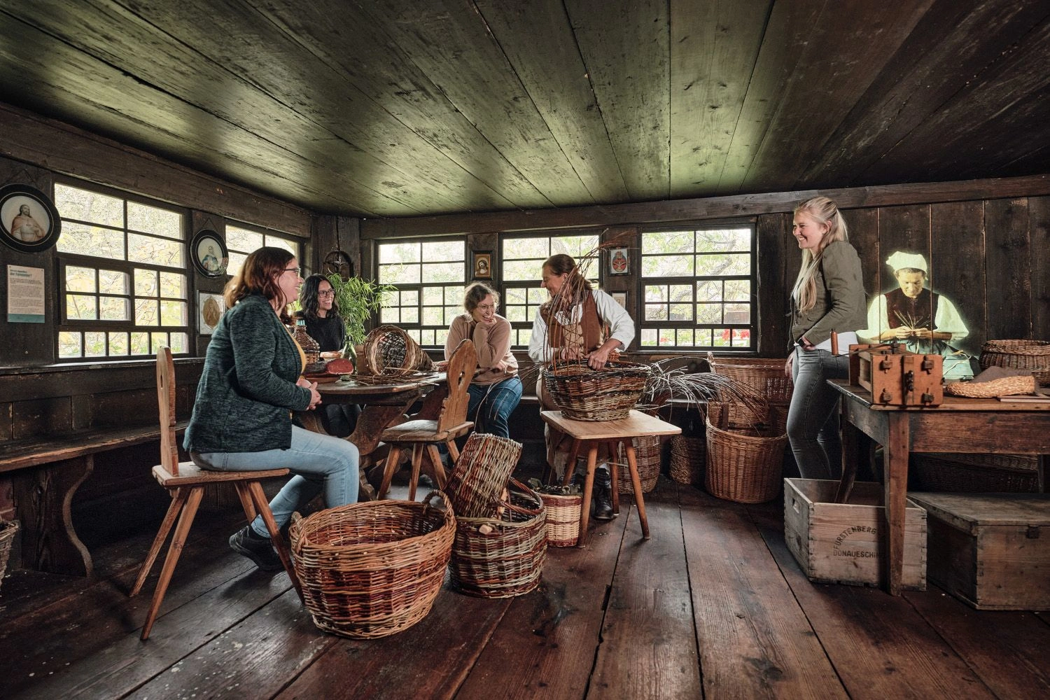 Frauen sitzen an einem Tisch und flechten Körbe