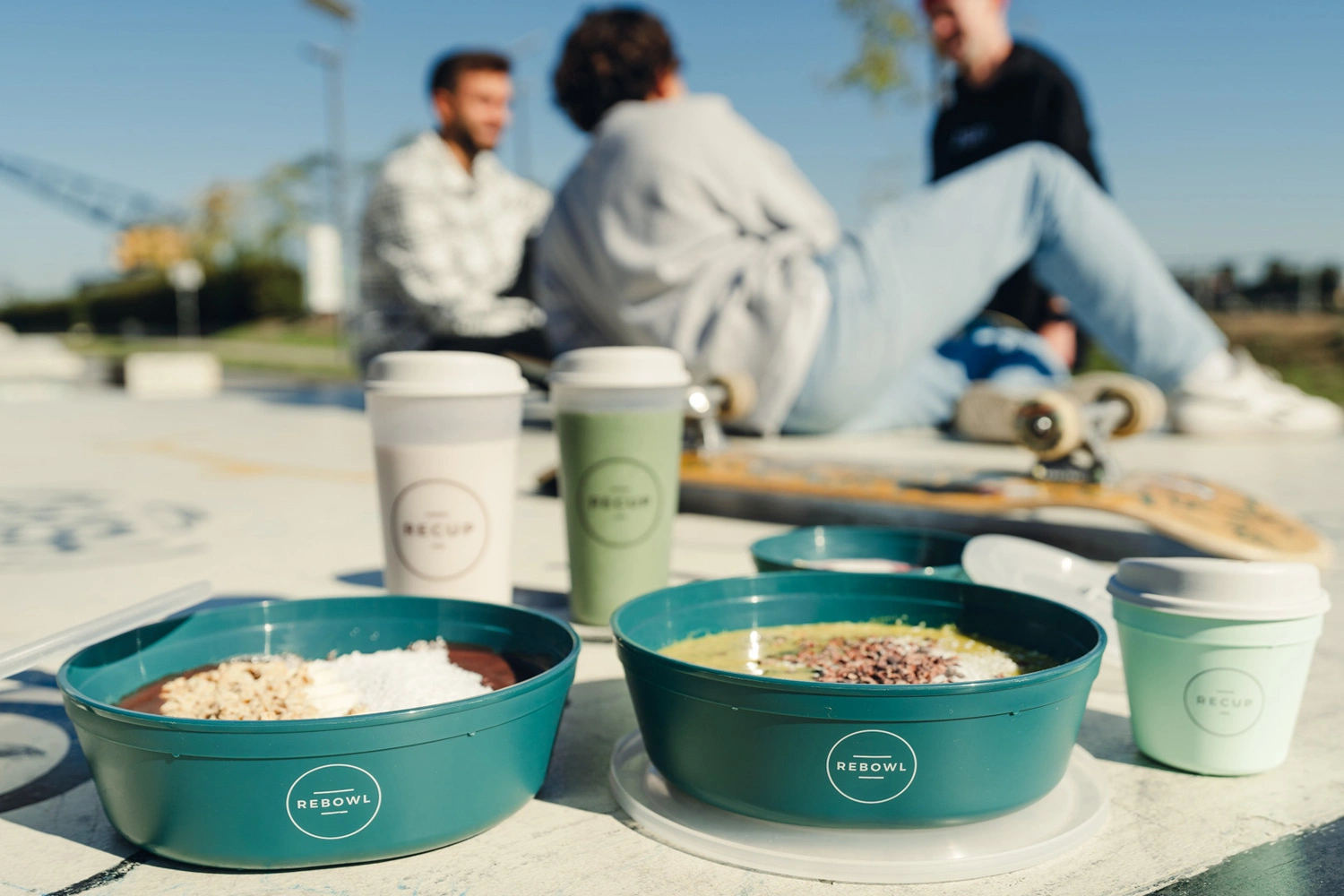 Junge Menschen genießen To-go und Take-away mit dem Mehrwegsystem Recup und Rebowl.