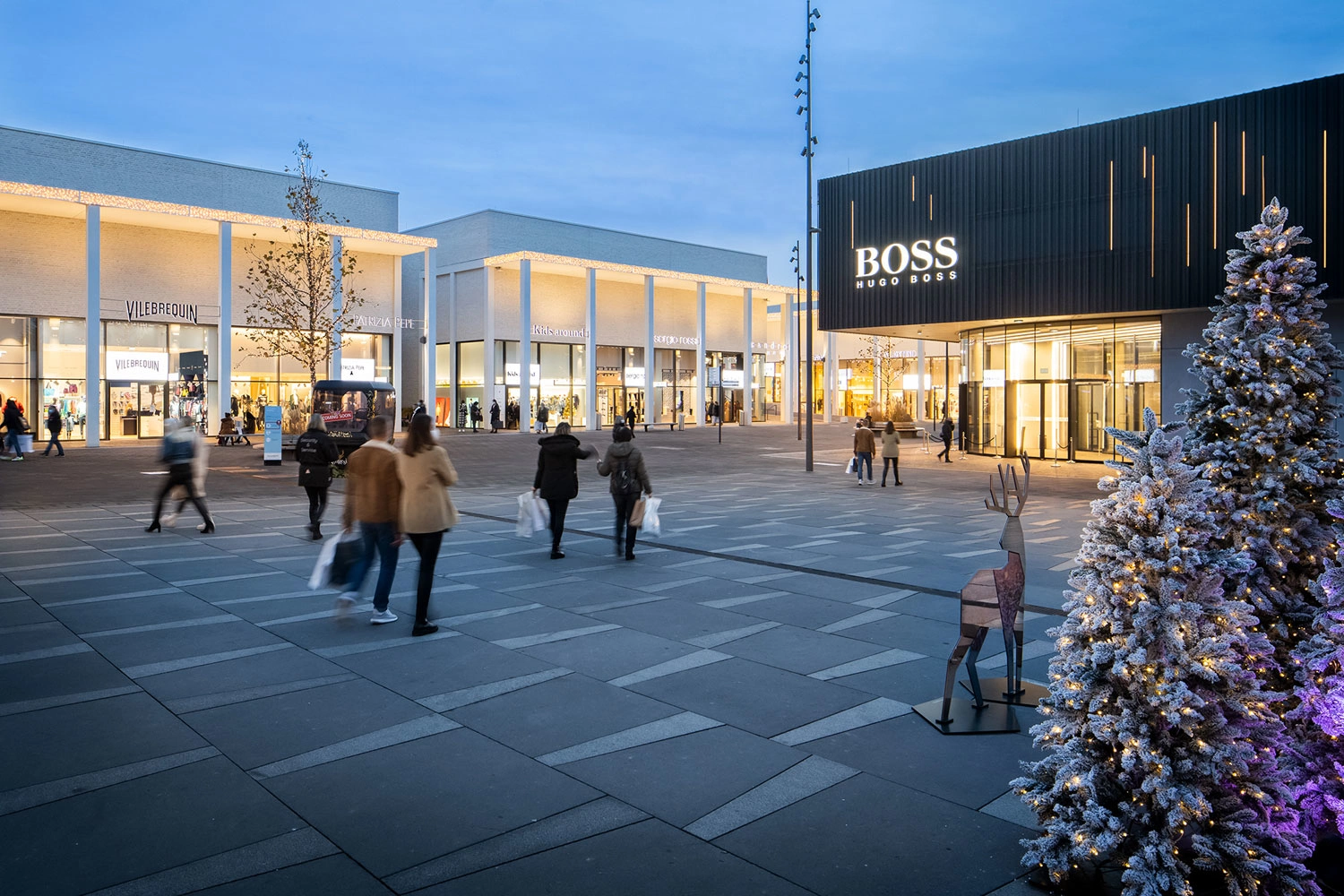 Various stores and stores are located around a square decorated for Christmas.