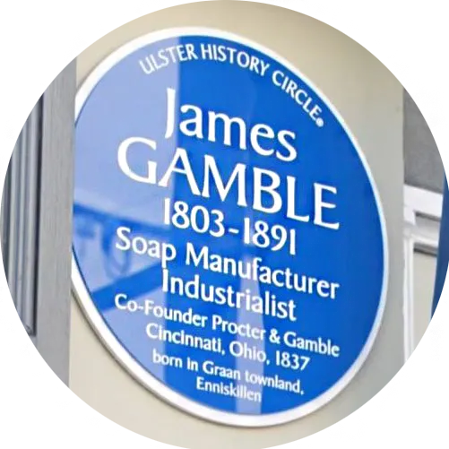 Blue heritage plaque reading “James Gamble 1803–1891, Soap Manufacturer, Industrialist, Co-founder Procter & Gamble” mounted on a building exterior.