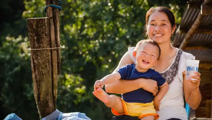 Woman holding a smiling baby and a glass of purified water