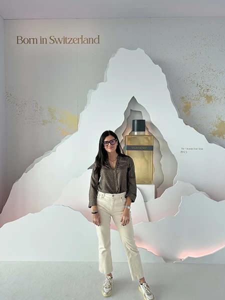 Woman standing in front of a Pantene display featuring a large cut-out mountain design and the text “Born in Switzerland