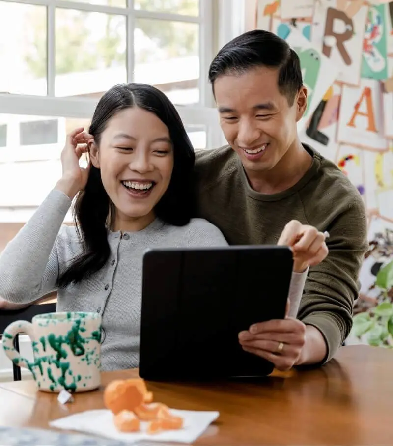 A couple smiling while looking at a tablet