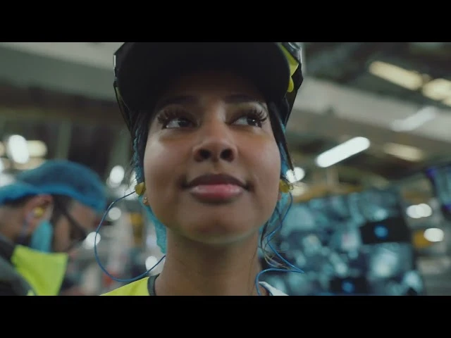 Factory worker wearing safety equipment on a production floor, highlighting P&G manufacturing, quality standards, and product innovation.