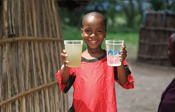 Child holding non-purified and P&G purified glass of water