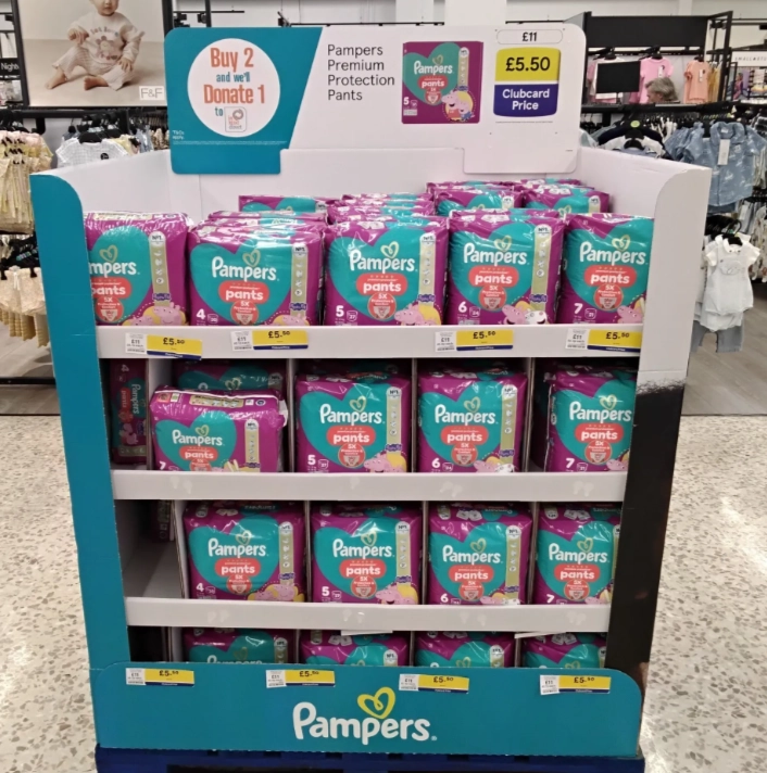 Pampers Premium Protection Pants displayed in-store, promoting a buy two, donate one initiative for families in need