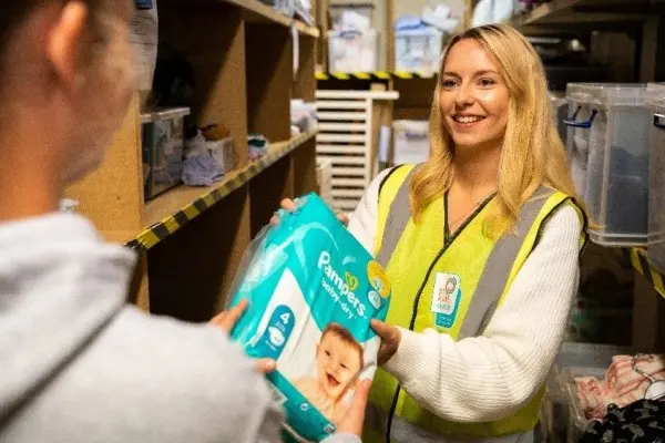 Woman giving Pampers product to a person
